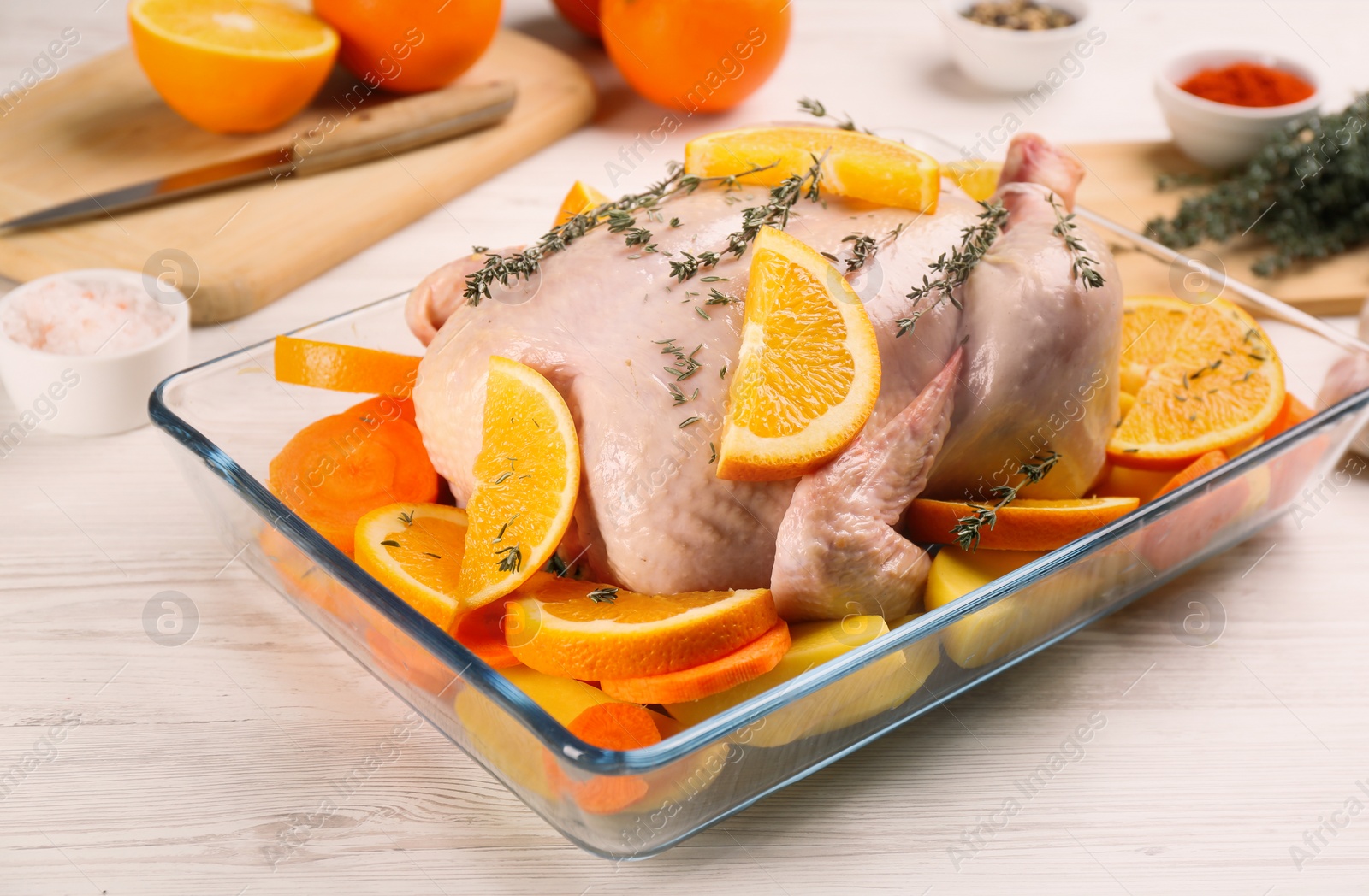 Photo of Raw chicken with orange slices and potatoes on white wooden table