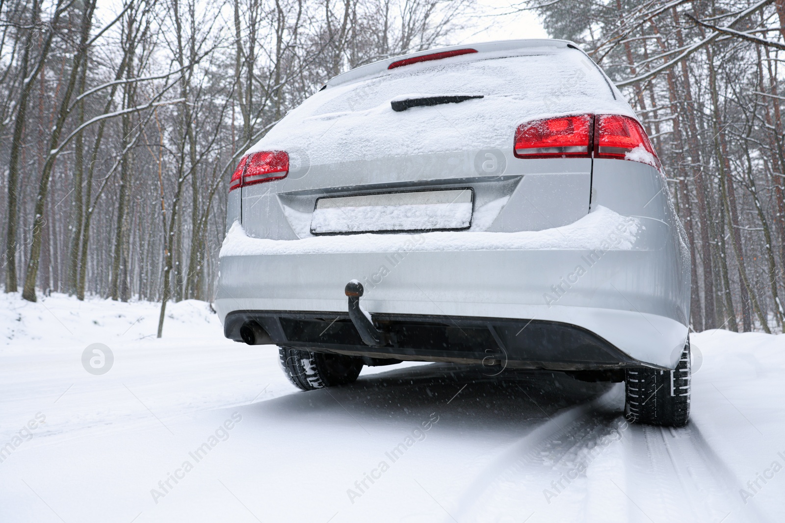 Photo of Car with winter tires on snowy road in forest