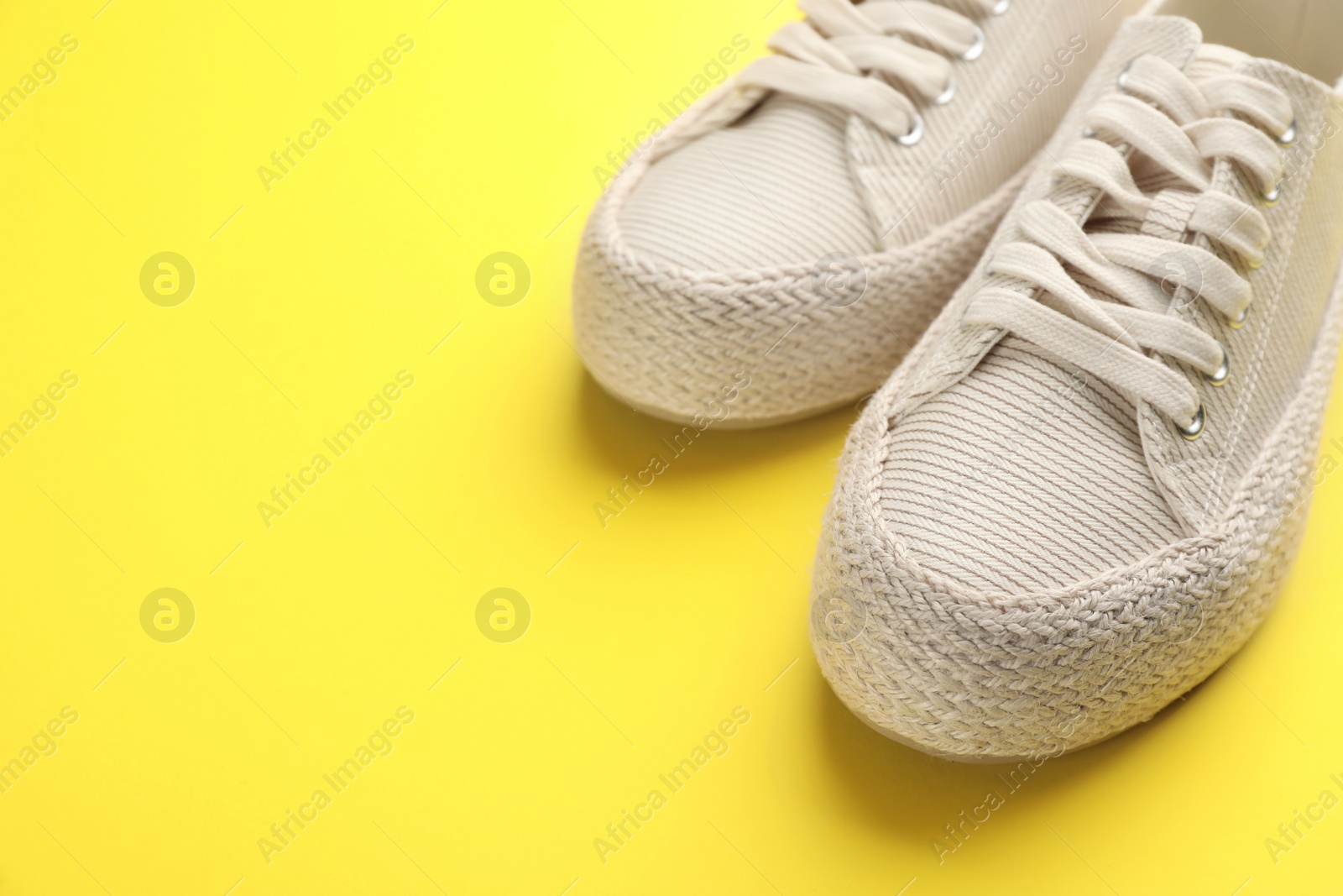 Photo of Pair of stylish comfortable shoes on yellow background,closeup. Space for text