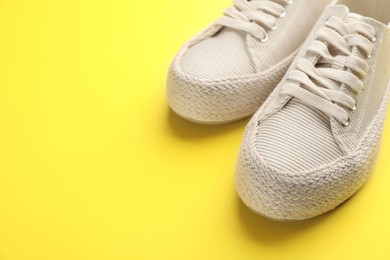 Pair of stylish comfortable shoes on yellow background,closeup. Space for text