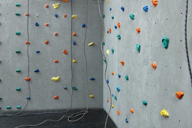 Photo of Climbing wall with holds and ropes in gym. Extreme sport