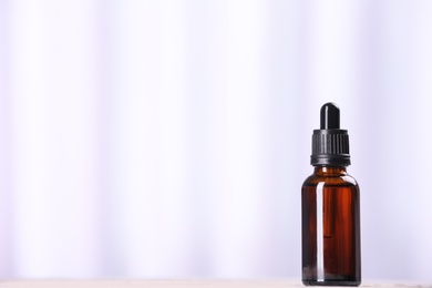 Bottle of essential oil on light background, space for text. Cosmetic product