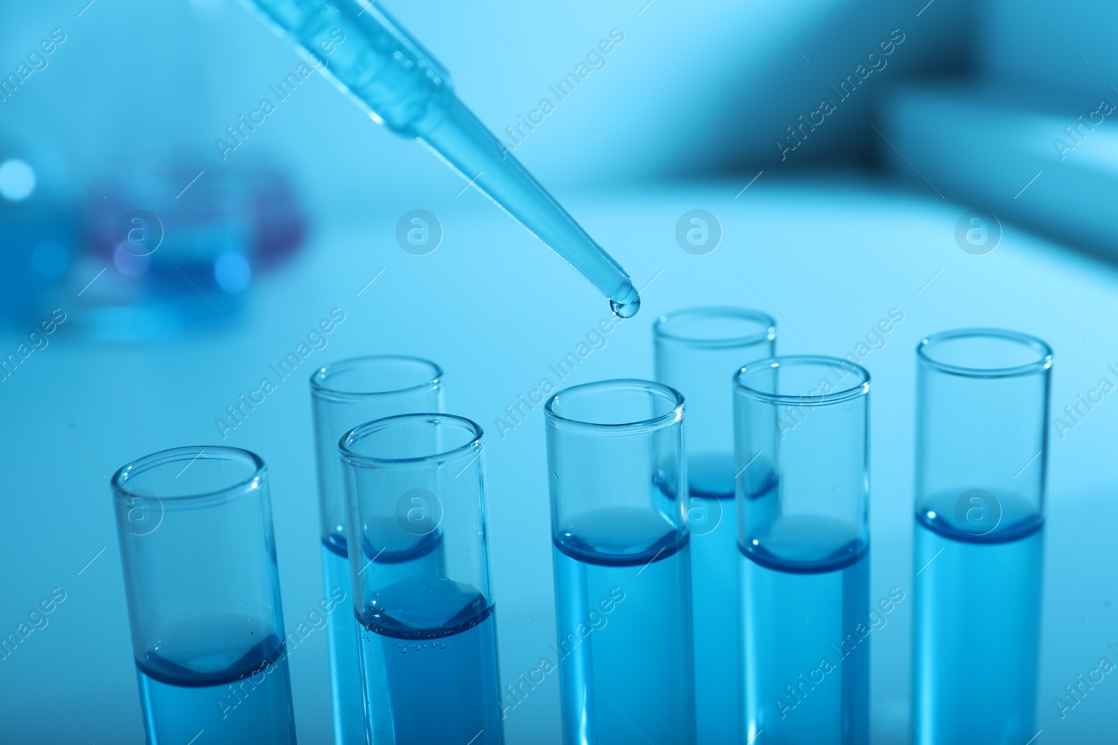 Photo of Dripping reagent into test tube with blue liquid, closeup. Laboratory analysis