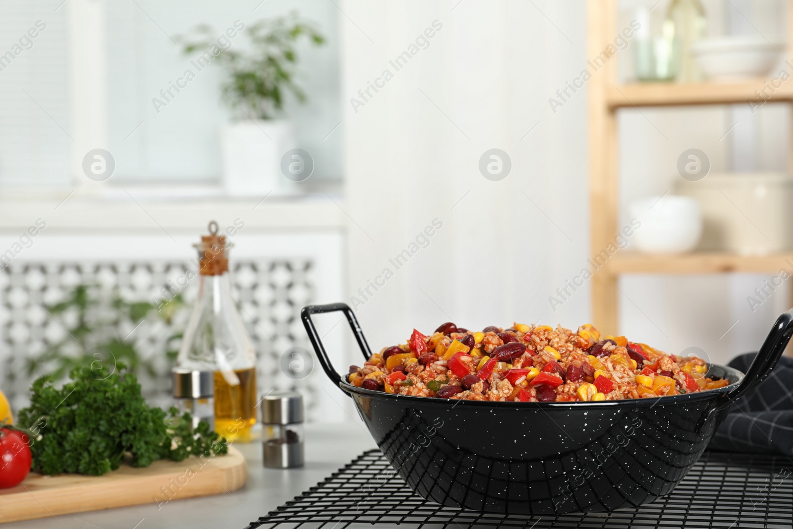 Photo of Pan with tasty chili con carne on gray table. Space for text
