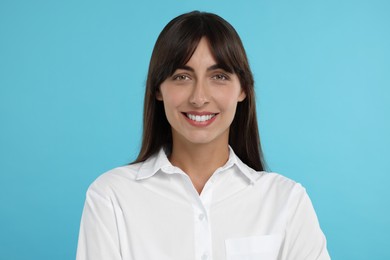 Portrait of happy secretary on light blue background