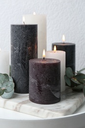 Photo of Burning candles and green branches on table