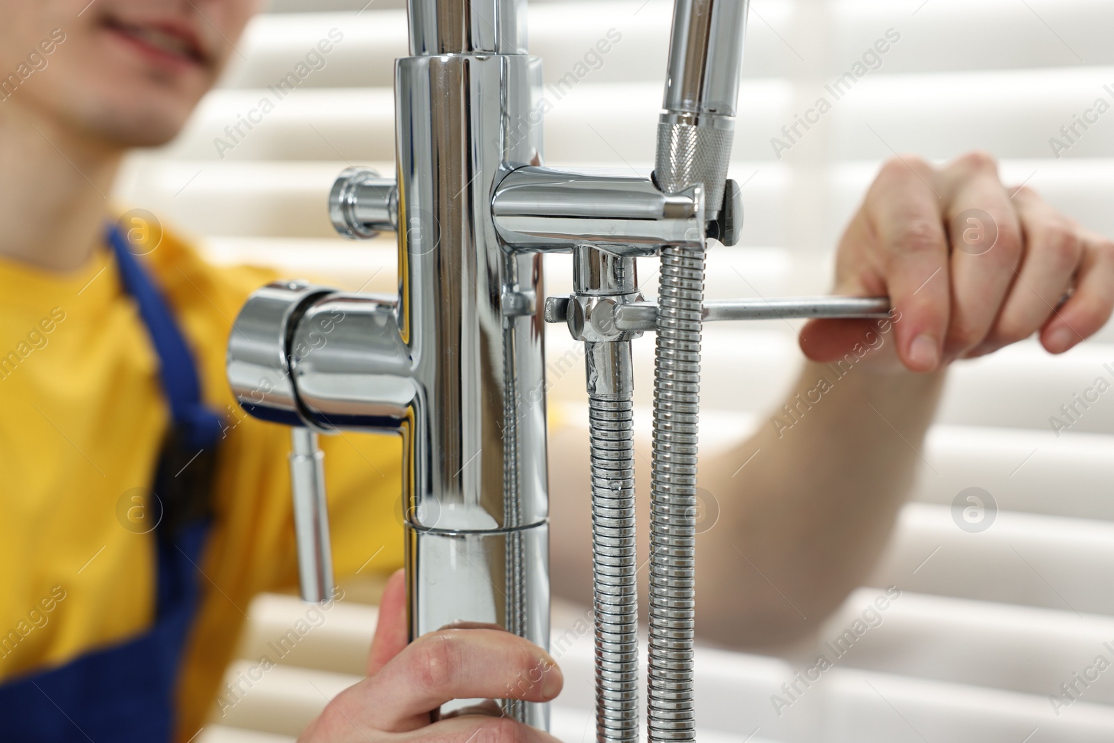 Photo of Plumber repairing faucet with spanner in bathroom, closeup