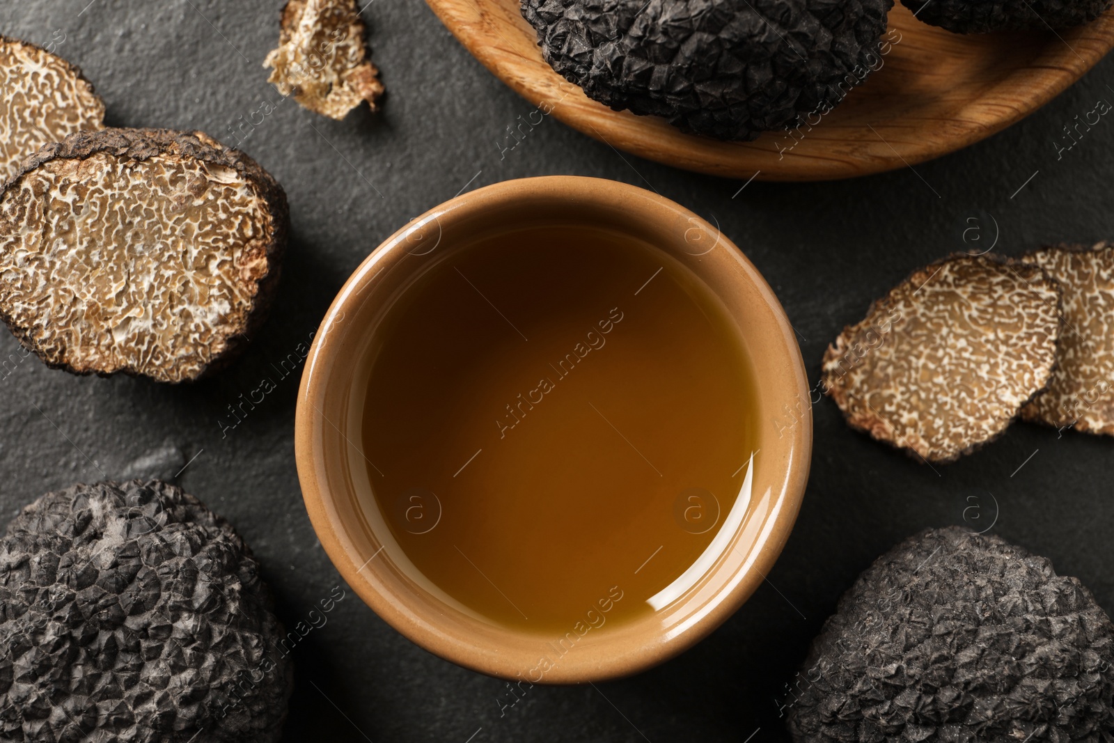 Photo of Bowl of truffle oil on slate table, flat lay