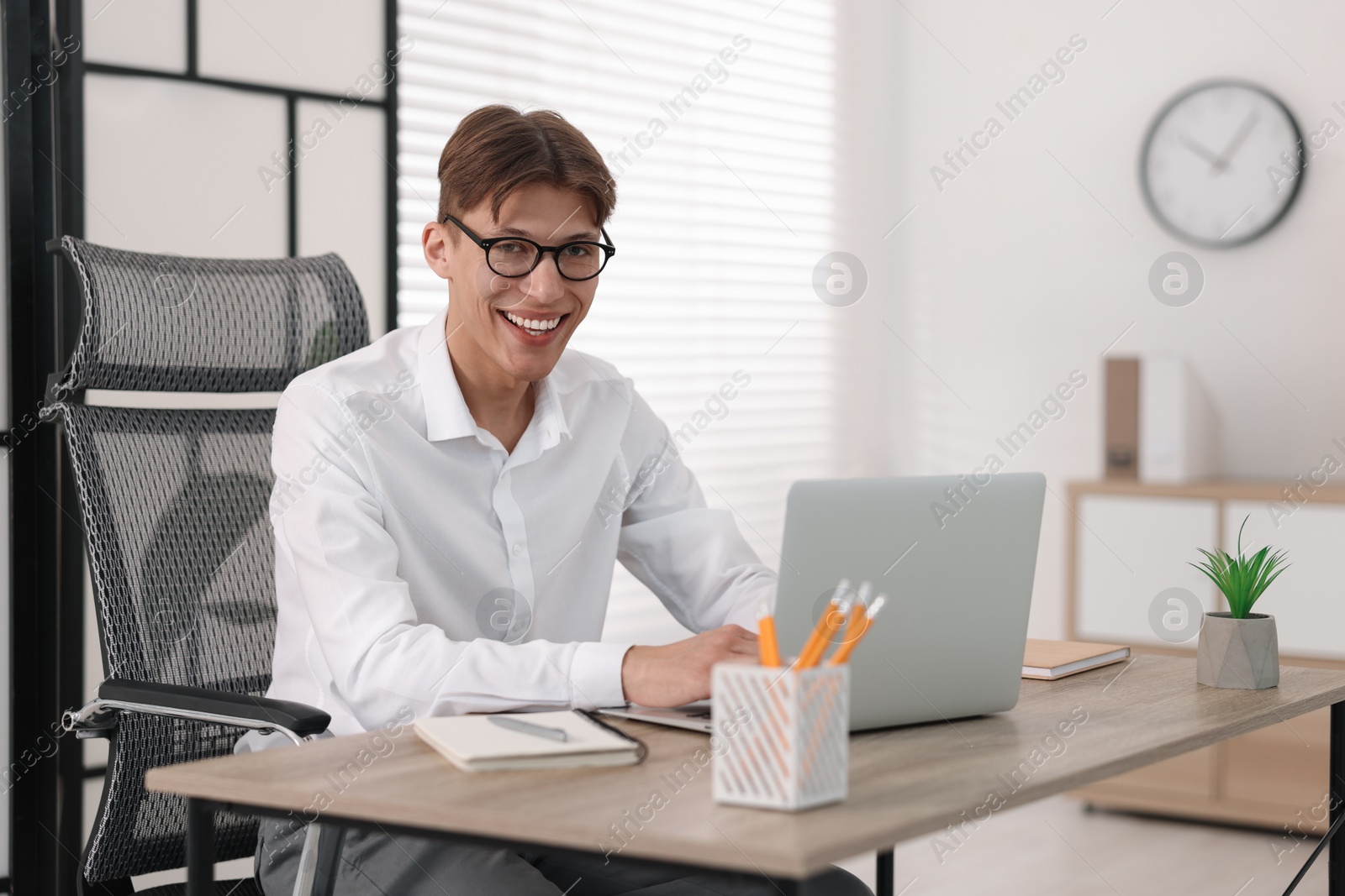 Photo of Man watching webinar at wooden table in office