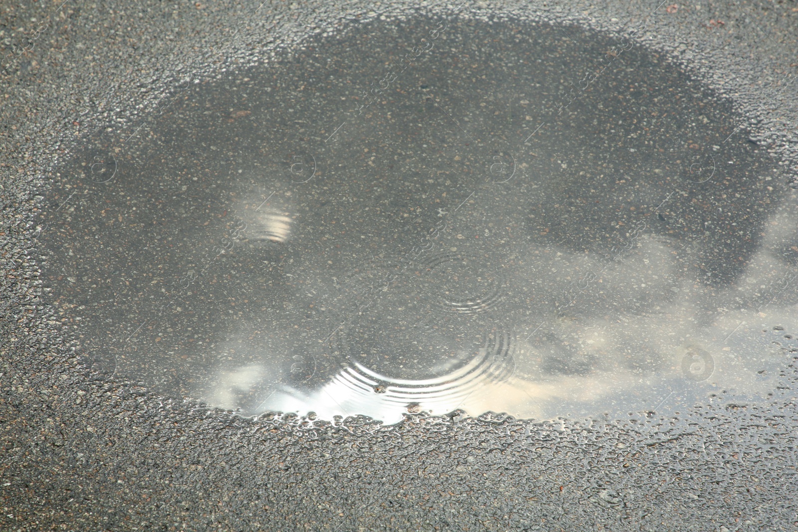 Photo of View of puddle on asphalt outdoors. Rainy day