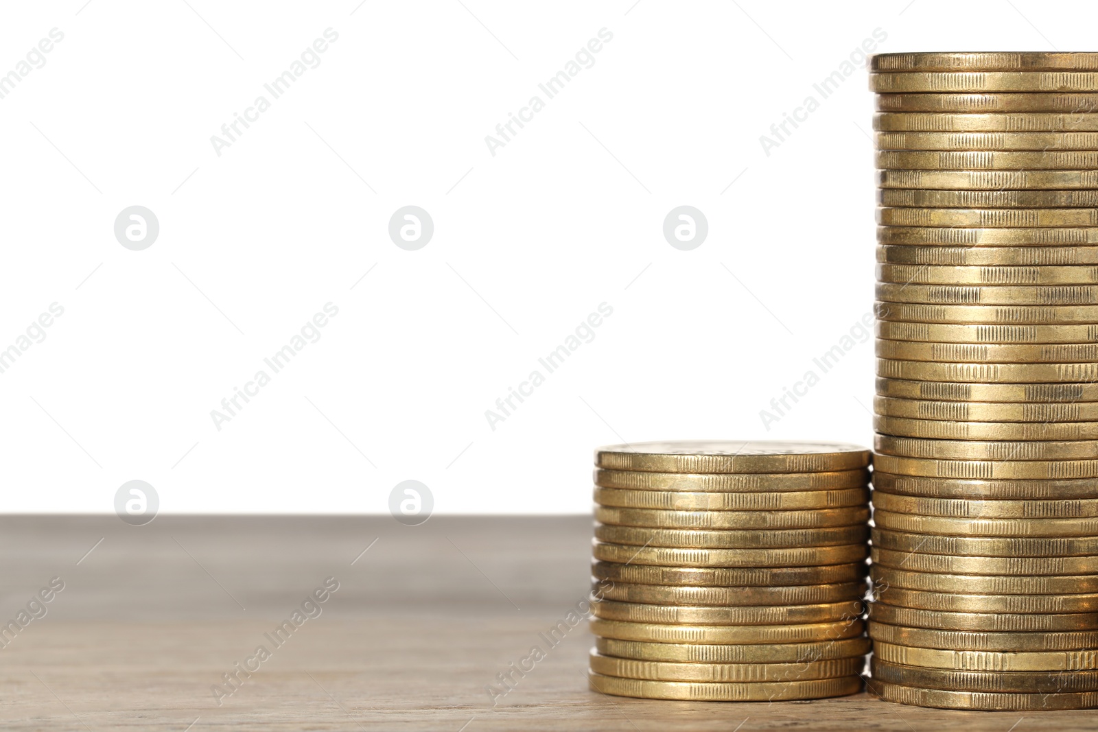 Photo of Many golden coins stacked on wooden table against white background, space for text