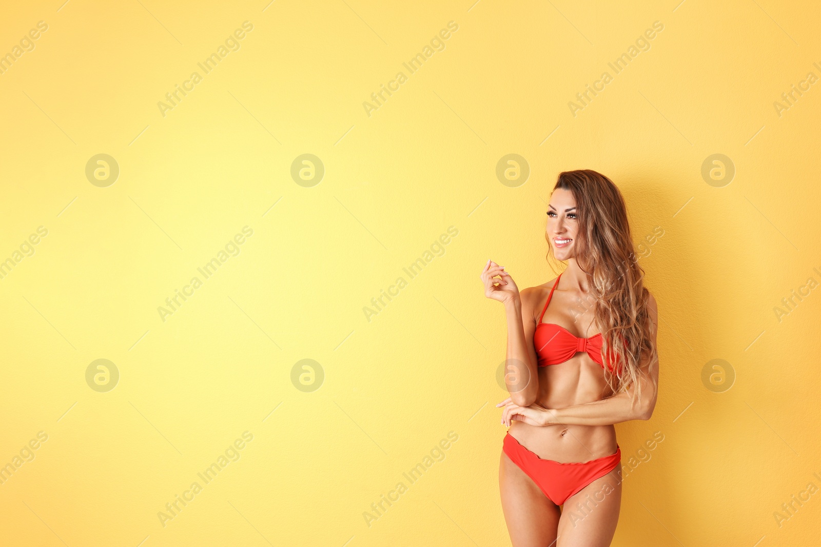 Photo of Pretty sexy woman with slim body in stylish bikini on color background, space for text