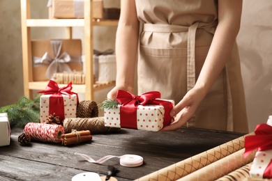 Photo of Woman holding Christmas gift over wooden table