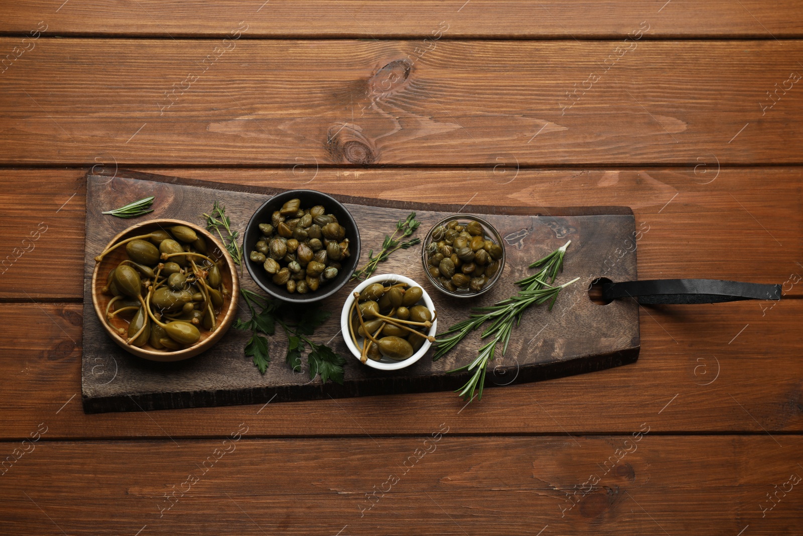 Photo of Tasty capers and herbs on wooden table, top view