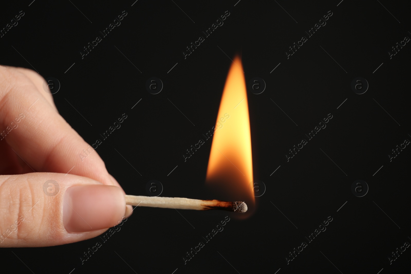 Photo of Woman holding burning match on black background, closeup. Space for text