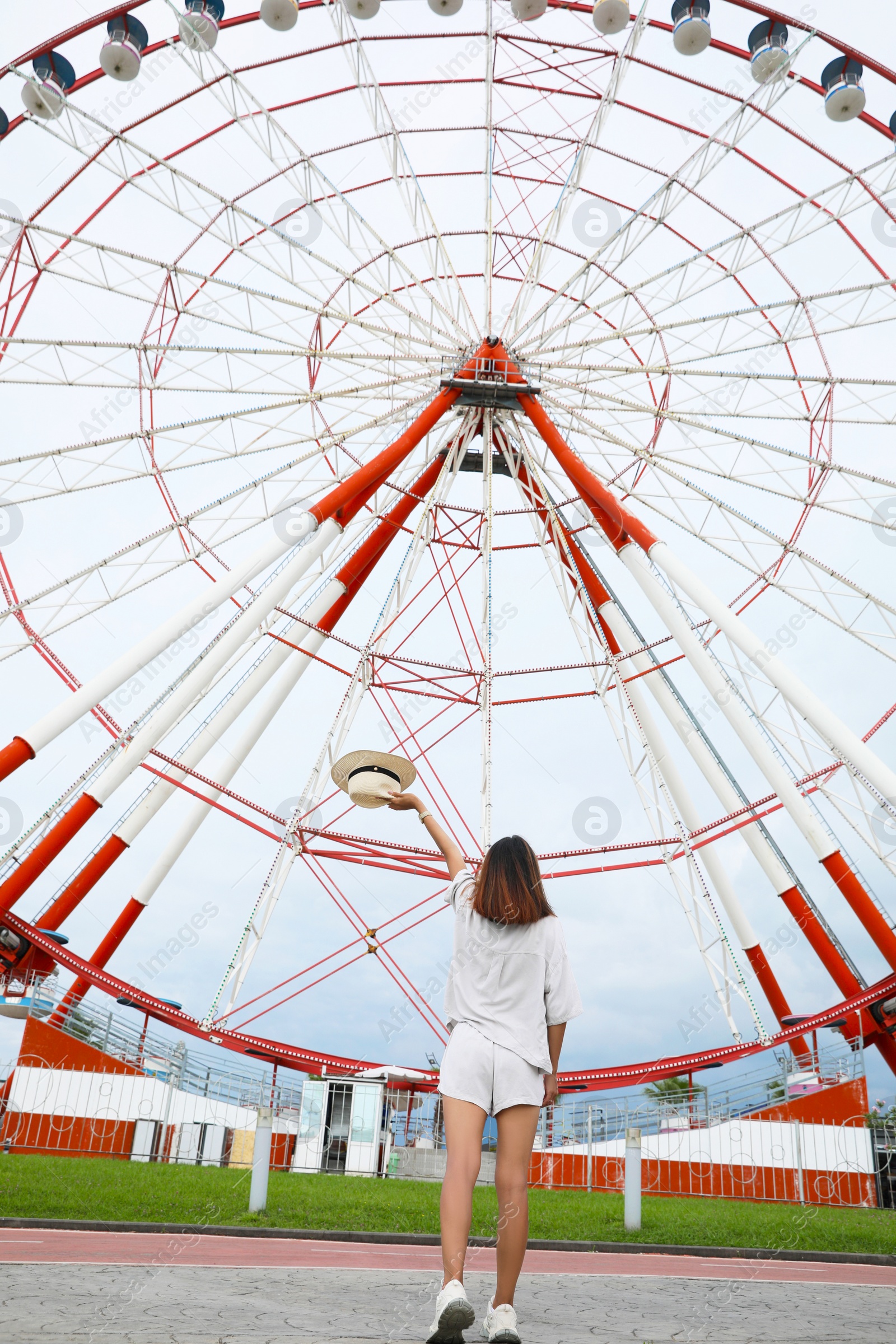 Photo of Young woman near Ferris wheel outdoors, low angle view