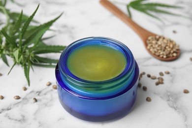 Photo of Jar of hemp cream on marble table, closeup. Organic cosmetics