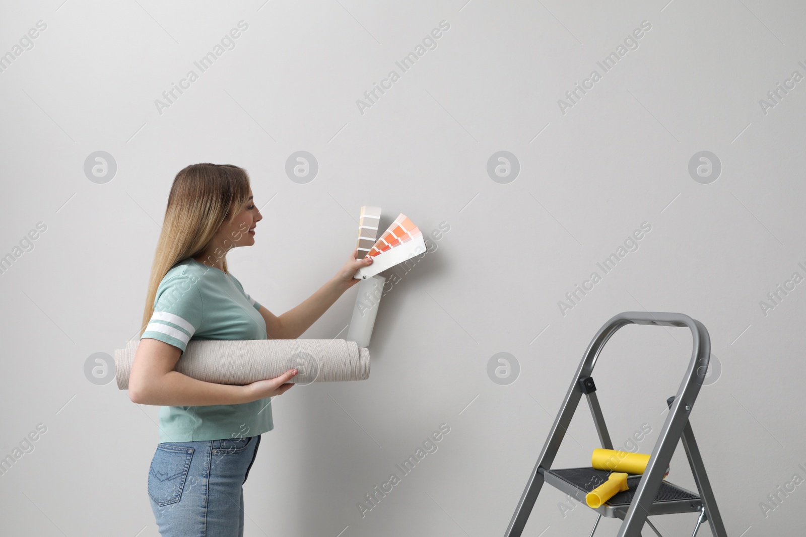 Photo of Woman with palette choosing wall paper color indoors