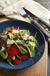 Plate with delicious beet salad on wooden board, closeup