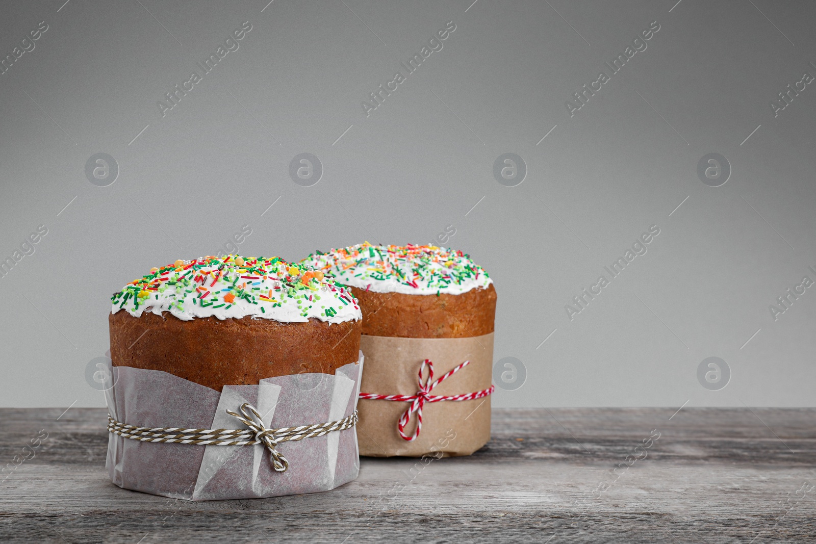 Photo of Traditional Easter cakes with sprinkles on wooden table, space for text