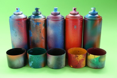 Photo of Many spray paint cans with caps on green background