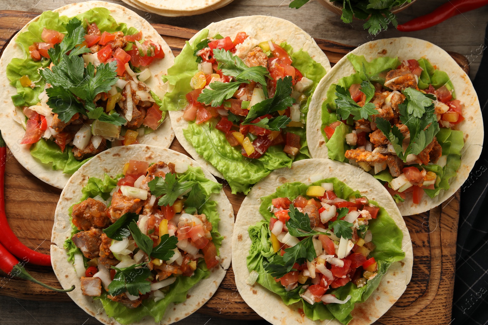 Photo of Delicious tacos with vegetables and meat on wooden table, flat lay