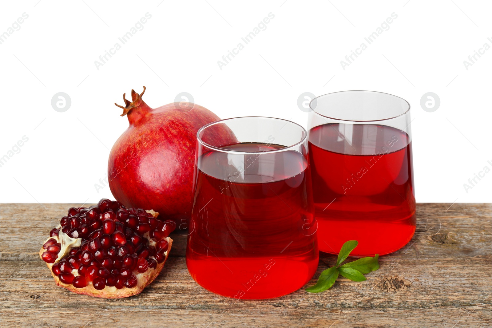 Photo of Refreshing pomegranate juice in glasses, leaves and fruits on wooden table against white background