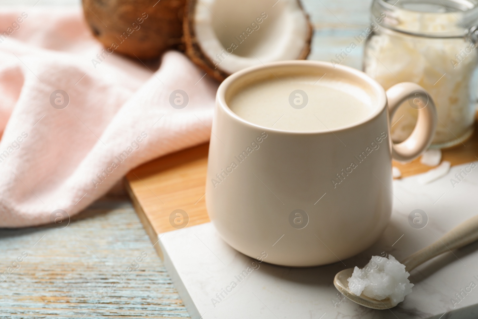 Photo of Delicious coffee with organic coconut oil on white wooden table