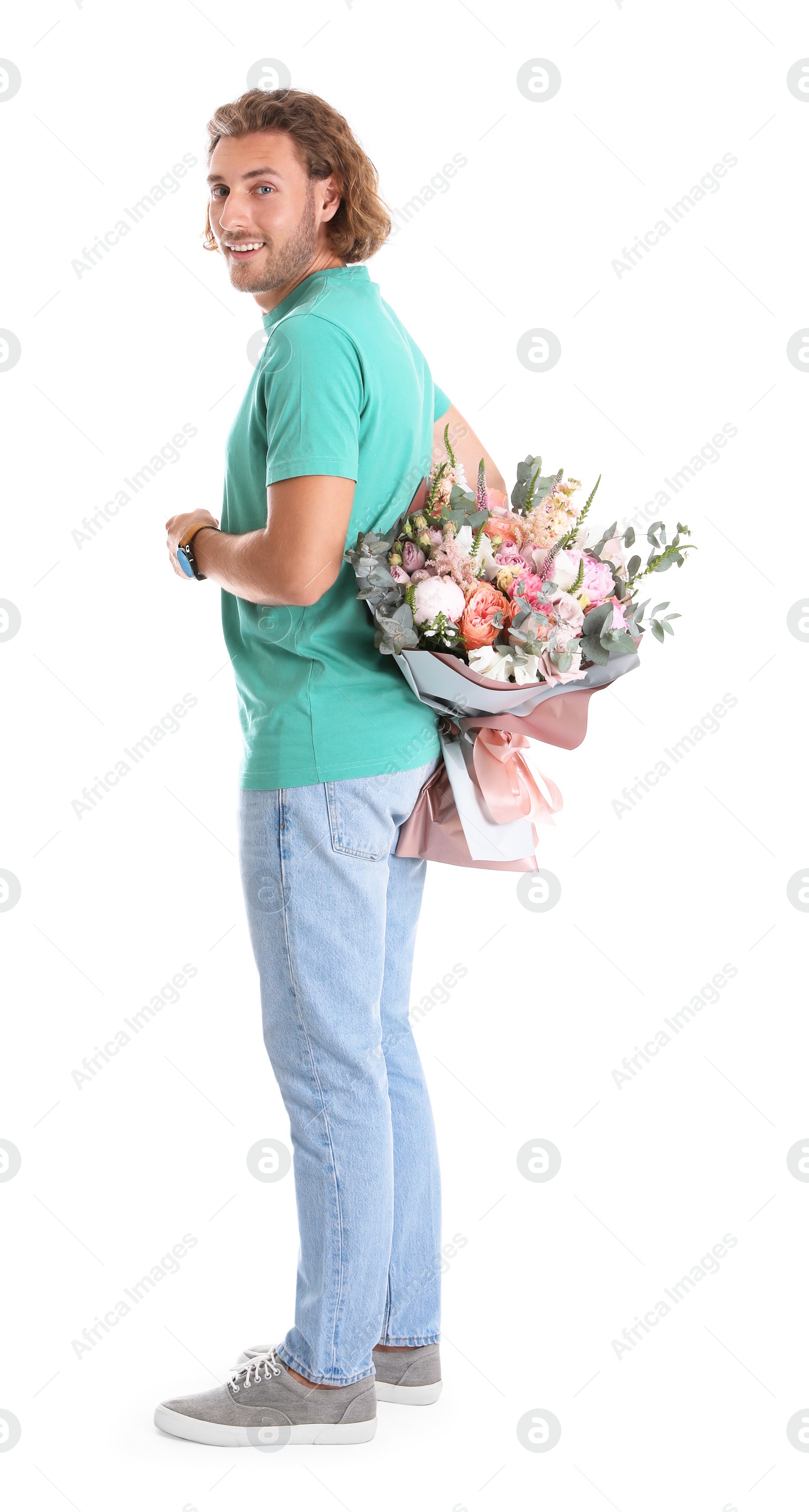 Photo of Young handsome man hiding beautiful flower bouquet behind his back on white background