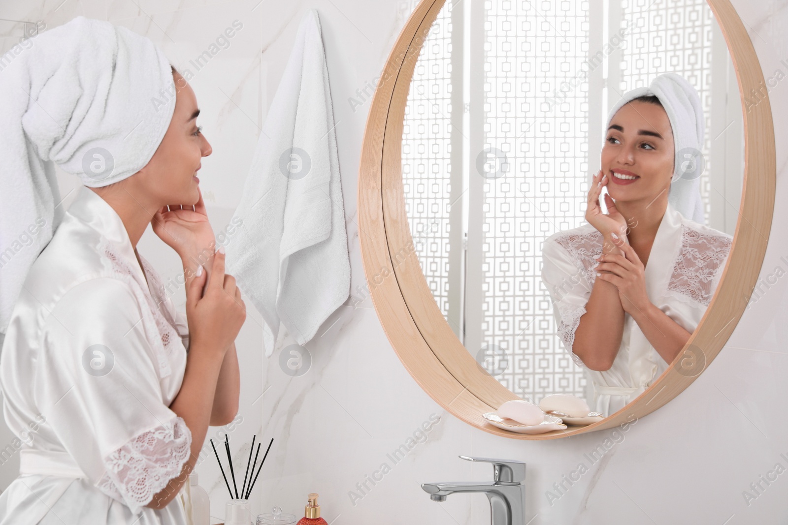 Photo of Beautiful young woman with perfect skin near mirror in bathroom. Facial wash