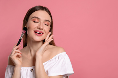 Beauty blogger doing makeup on pink background. Space for text