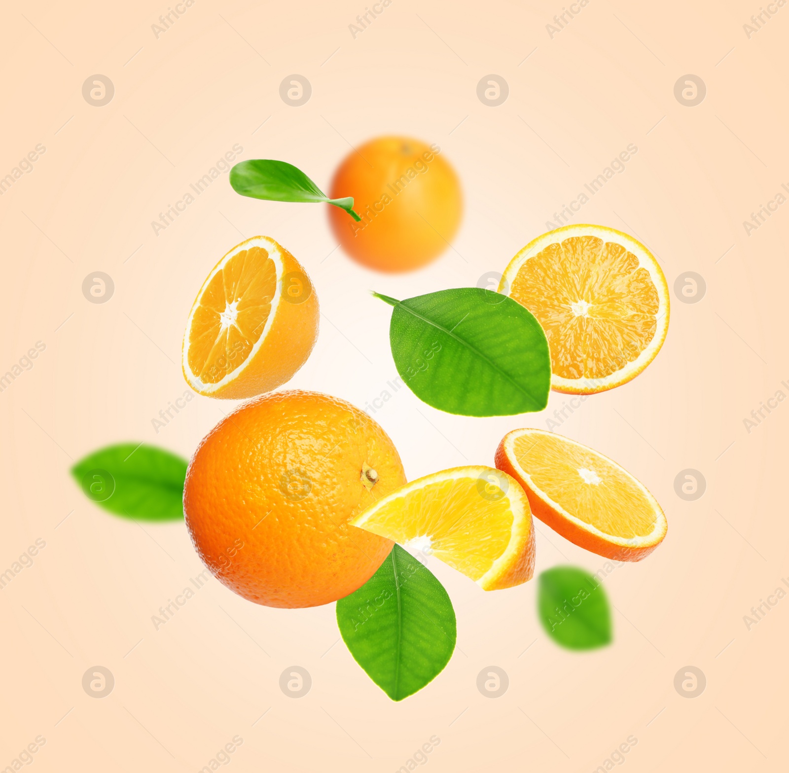 Image of Cut and whole oranges with green leaves flying on beige background