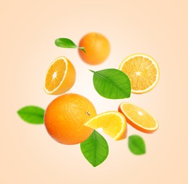 Cut and whole oranges with green leaves flying on beige background