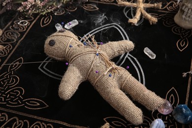 Voodoo doll with pins and dried flowers on table