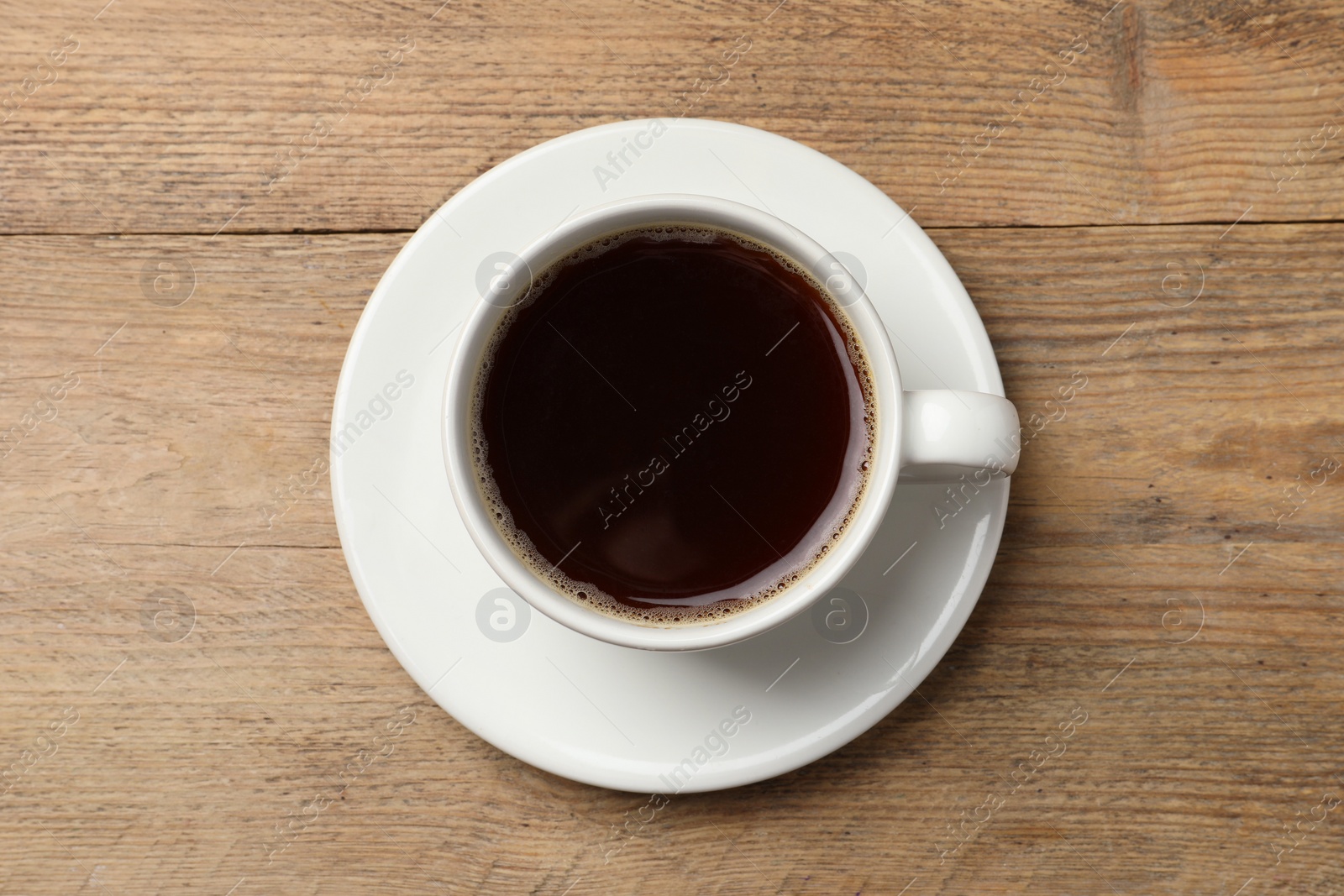 Photo of Cup of aromatic coffee on wooden table, top view