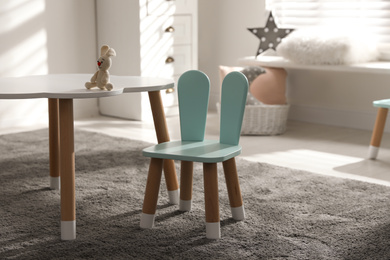 Photo of Small table and chair with bunny ears in children's room interior