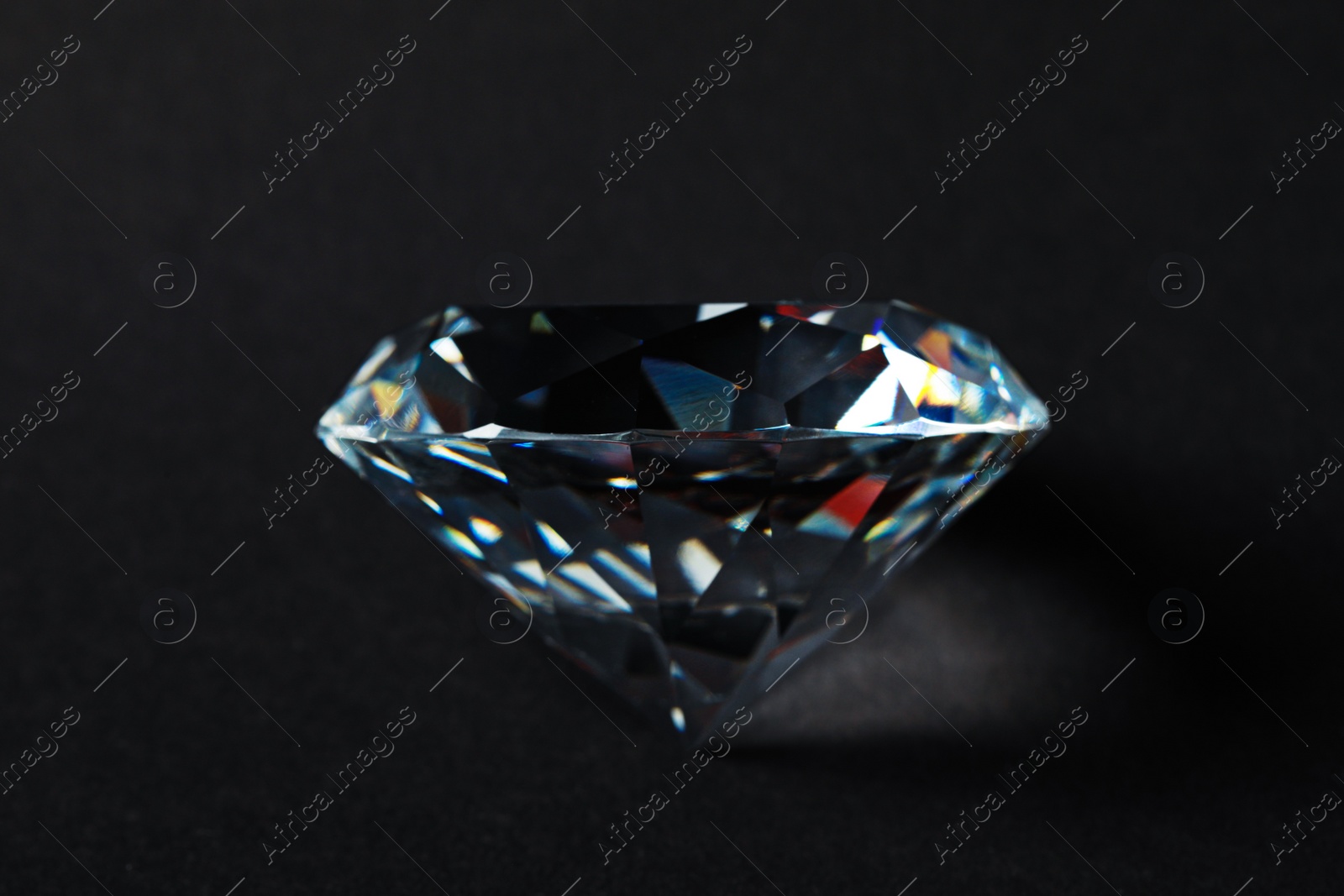 Photo of Beautiful dazzling diamond on dark background, closeup. Precious gemstone