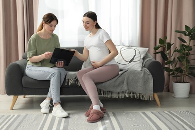 Photo of Doula working with pregnant woman on sofa at home. Preparation for child birth