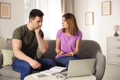 Sad couple counting money in living room