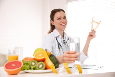 Nutritionist with caliper and glass of water at desk in office