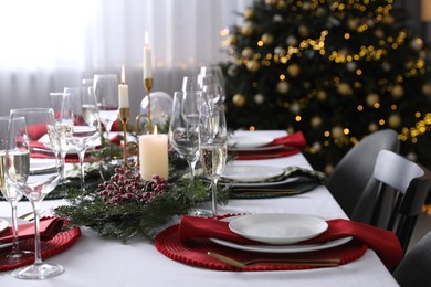 Photo of Christmas table setting with festive decor and dishware indoors