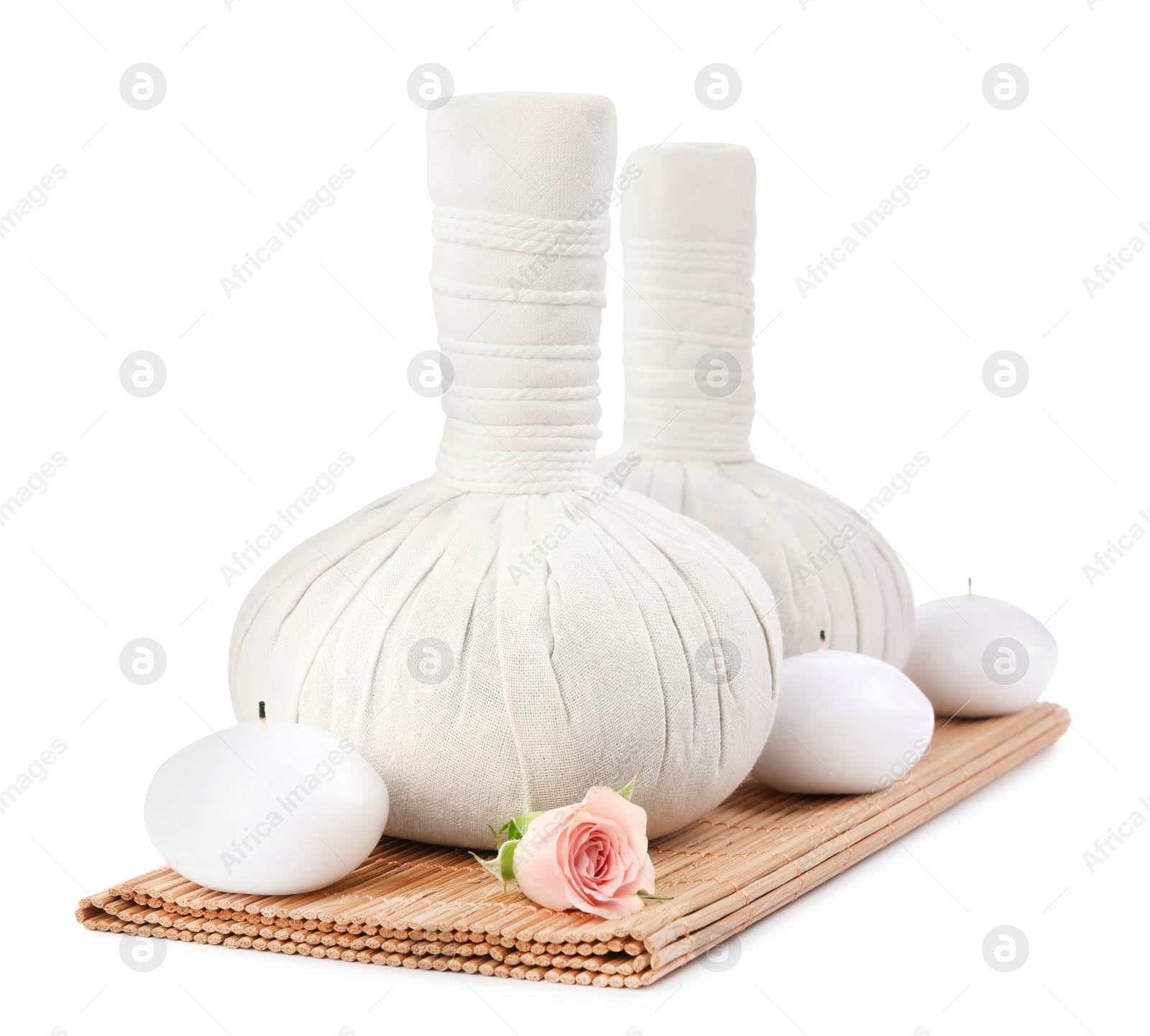 Photo of Herbal massage bags, rose and candles on white background. Spa supply