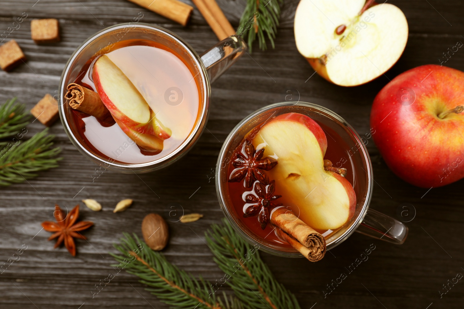 Photo of Aromatic hot mulled cider on black wooden table, flat lay