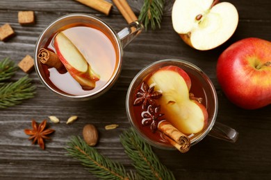 Photo of Aromatic hot mulled cider on black wooden table, flat lay