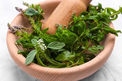 Photo of Mortar with pestle and mint leaves on light grey table, closeup