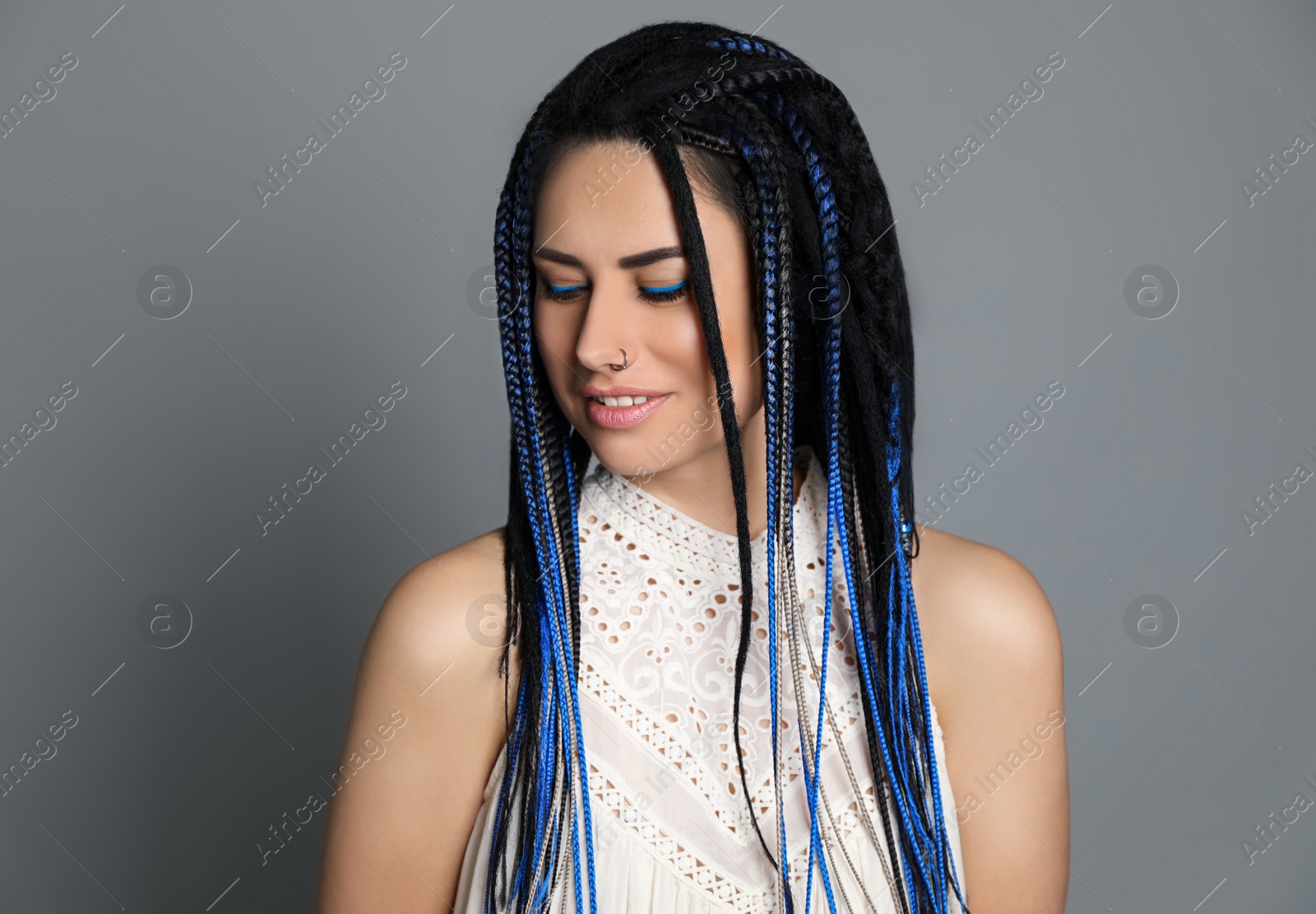 Photo of Beautiful young woman with nose piercing and dreadlocks on grey background