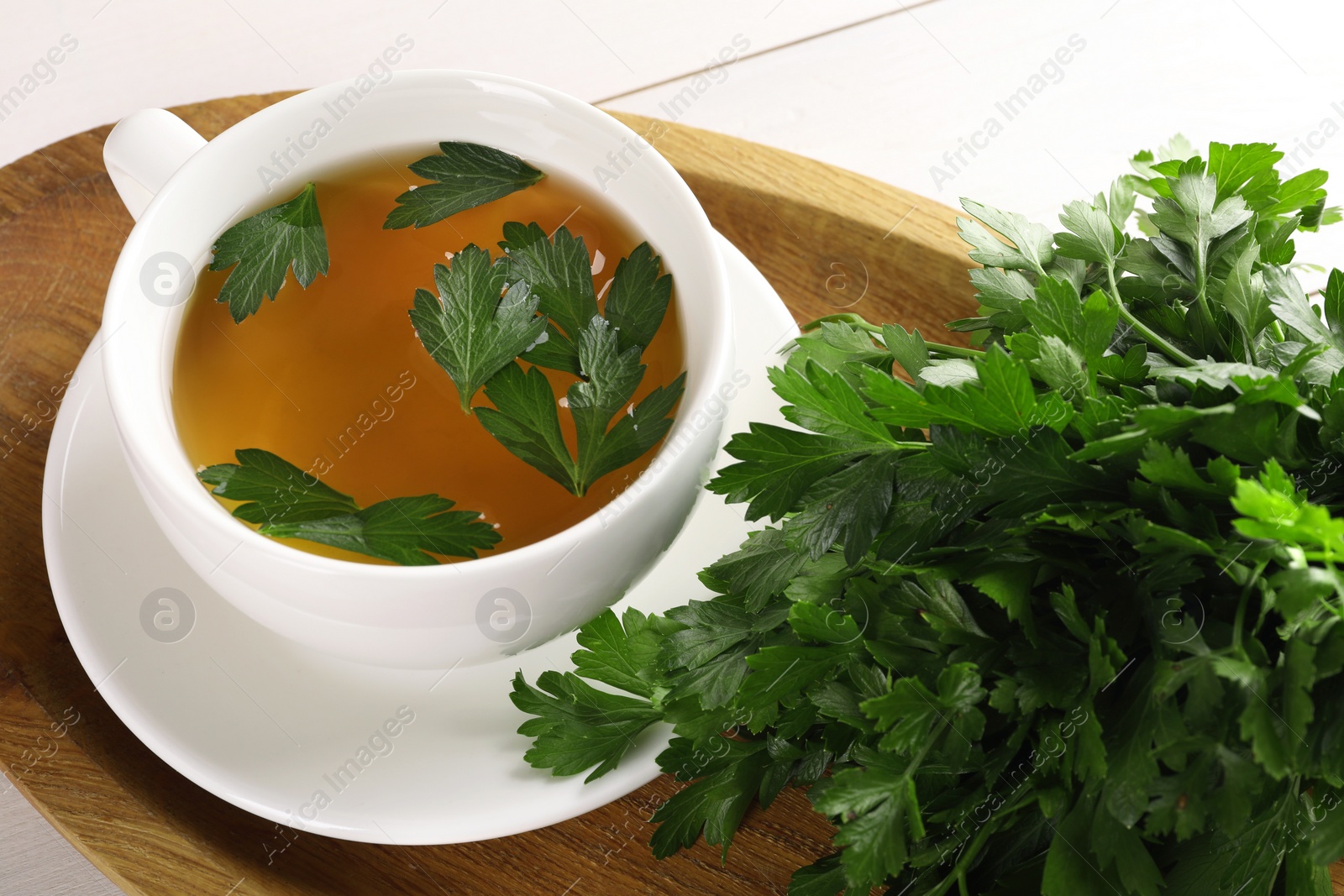 Photo of Aromatic herbal tea and fresh parsley on white wooden table, above view