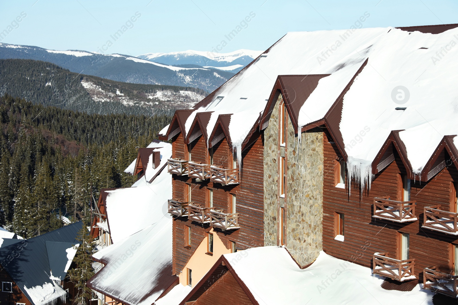 Photo of Modern cottage covered with snow in mountains on sunny day. Winter vacation