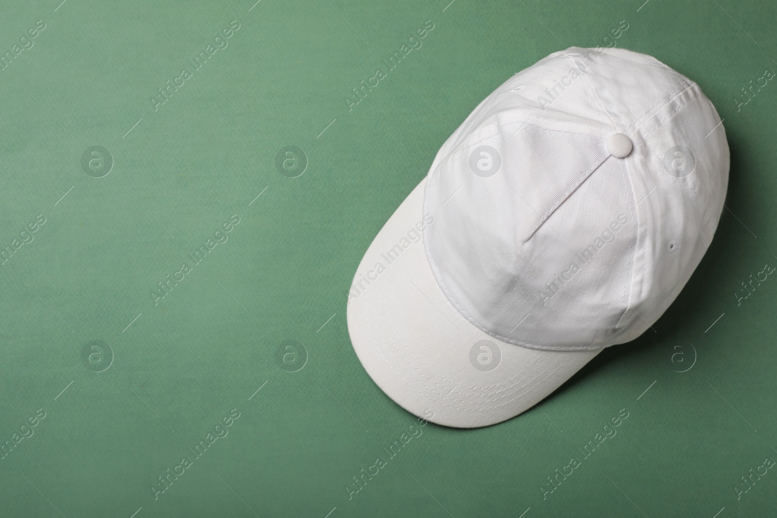 Photo of Baseball cap on green background, top view. Space for text