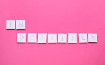 Photo of Motivation concept. Changing word from Impossible into Possible by removing paper with letters I and M on pink background, top view